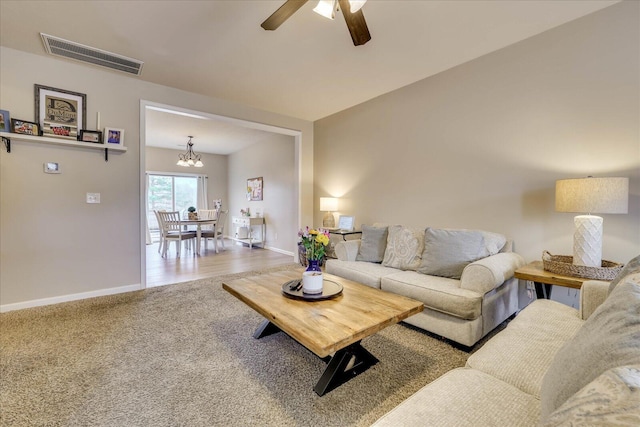 carpeted living room featuring ceiling fan with notable chandelier