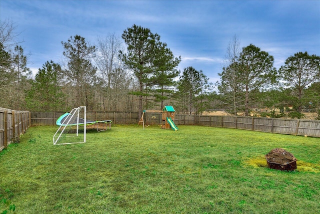 view of yard featuring a fire pit, a playground, and a trampoline