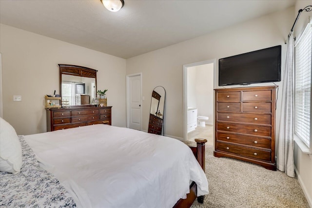 bedroom featuring light colored carpet and ensuite bath