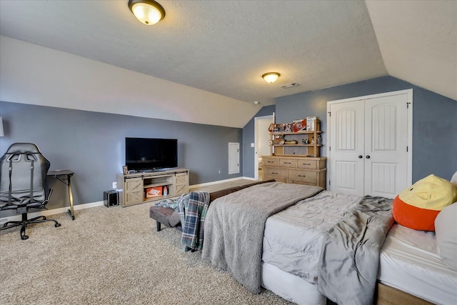 bedroom featuring a textured ceiling, vaulted ceiling, carpet, and a closet