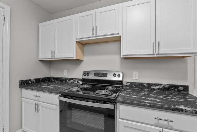 kitchen with white cabinets, dark stone countertops, and stainless steel electric range