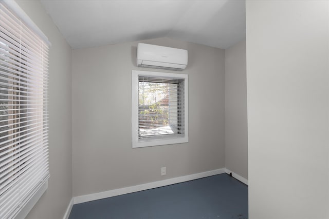 spare room with concrete floors, a wall unit AC, and lofted ceiling