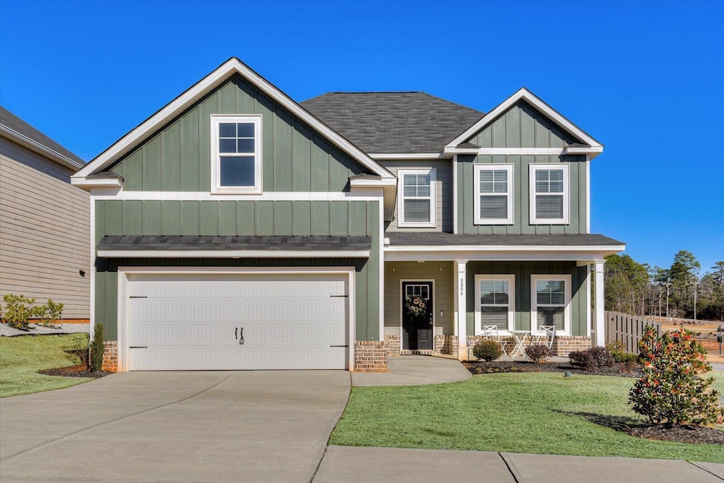 craftsman house with a garage, a front yard, and a porch