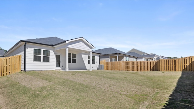 back of property with a fenced backyard, a lawn, and central air condition unit