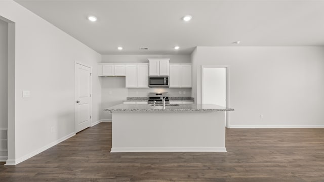 kitchen with white cabinets, recessed lighting, appliances with stainless steel finishes, a center island with sink, and baseboards