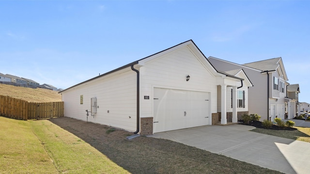 view of home's exterior with an attached garage, fence, a lawn, and driveway