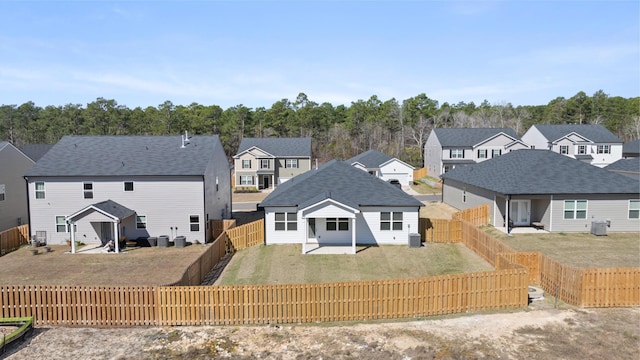 rear view of property featuring central AC unit, a yard, a fenced backyard, and a residential view