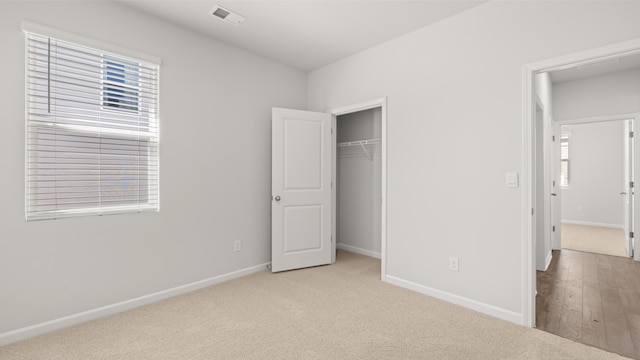 unfurnished bedroom with light carpet, baseboards, multiple windows, and visible vents