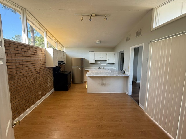 3314 Forest Estates Dr, Augusta, GA 30909 - kitchen with black electric range, freestanding refrigerator, a peninsula, a sink, and brick wall
