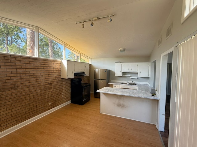 3314 Forest Estates Dr, Augusta, GA 30909 - kitchen with black electric range, freestanding refrigerator, brick wall, a peninsula, and vaulted ceiling