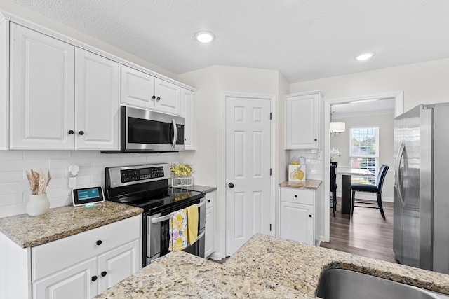 3235 Warwick Pl, Hephzibah, GA 30815 - kitchen with stainless steel appliances, white cabinets, light stone counters, decorative backsplash, and wood finished floors