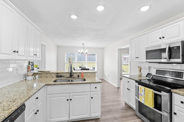 3235 Warwick Pl, Hephzibah, GA 30815 - kitchen featuring appliances with stainless steel finishes, a textured ceiling, a peninsula, tasteful backsplash, and white cabinetry