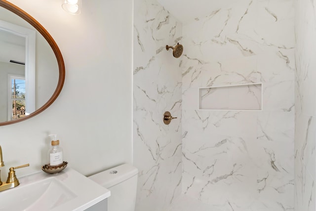 bathroom featuring tiled shower, vanity, and toilet