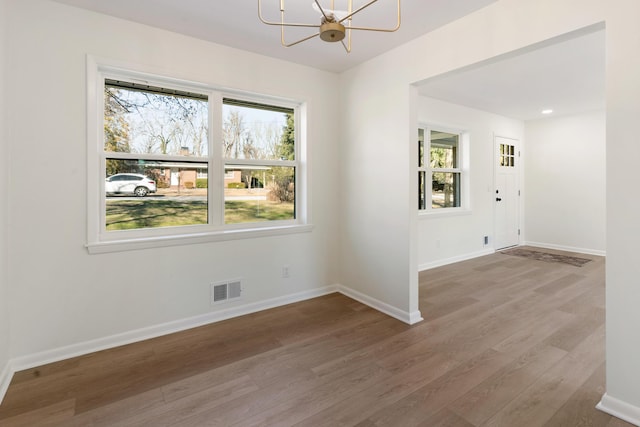 spare room with hardwood / wood-style flooring and a notable chandelier