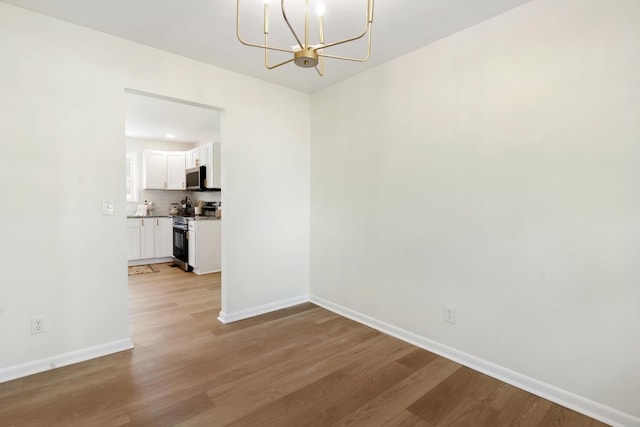 unfurnished dining area featuring a chandelier and light wood-type flooring