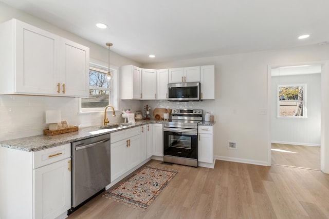 kitchen with light stone countertops, white cabinetry, sink, stainless steel appliances, and decorative backsplash