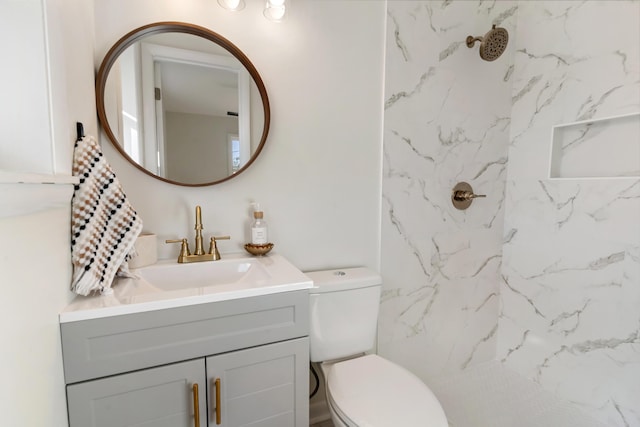 bathroom featuring a tile shower, vanity, and toilet