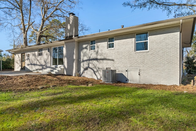 rear view of property with central AC and a lawn