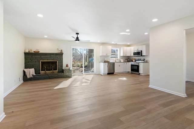 unfurnished living room featuring ceiling fan, a fireplace, and light hardwood / wood-style flooring