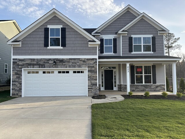 craftsman inspired home with a garage and a front lawn