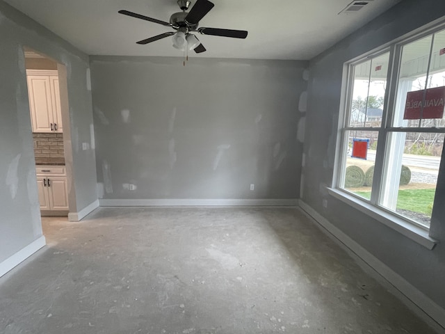 unfurnished room featuring a ceiling fan, visible vents, baseboards, and unfinished concrete floors