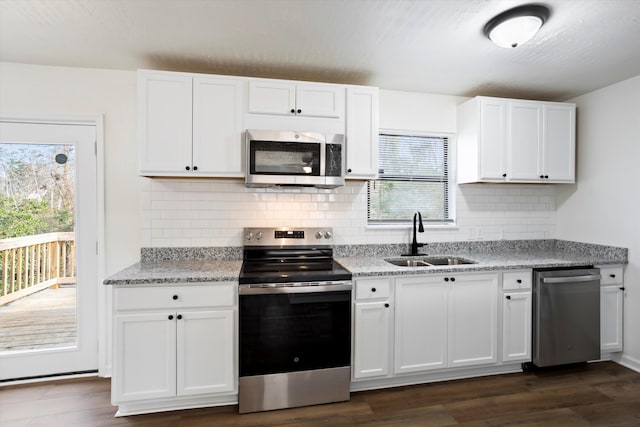 kitchen with light stone counters, stainless steel appliances, dark wood-type flooring, white cabinets, and a sink