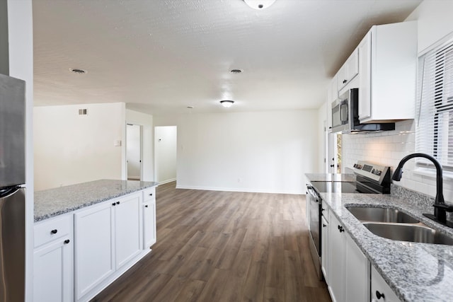 kitchen with white cabinets, light stone counters, stainless steel appliances, and a sink