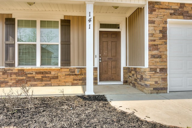 doorway to property featuring stone siding, a porch, and an attached garage