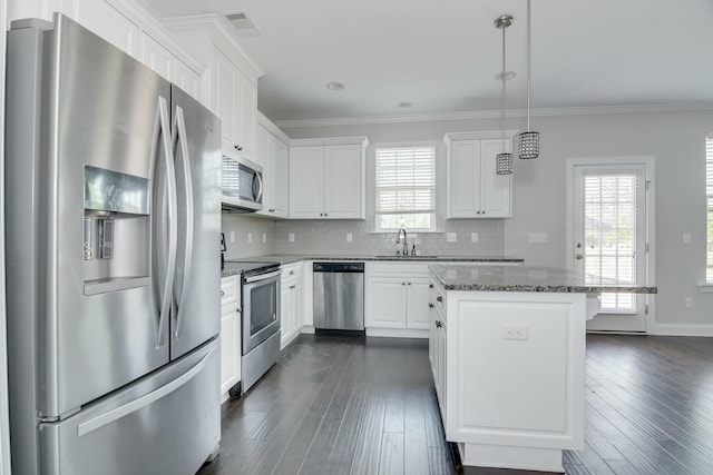 kitchen featuring a kitchen island, dark wood finished floors, a sink, stainless steel appliances, and tasteful backsplash