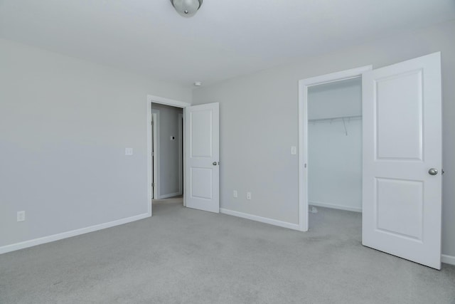 unfurnished bedroom featuring a closet, baseboards, carpet floors, and a spacious closet