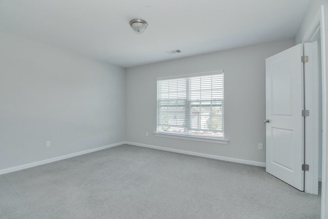 empty room featuring visible vents, light colored carpet, and baseboards