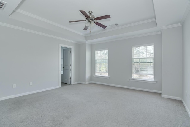 empty room with a tray ceiling, visible vents, light colored carpet, and a healthy amount of sunlight