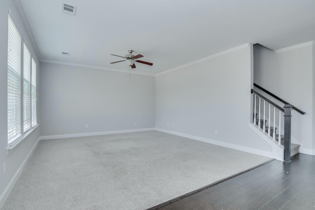 spare room featuring visible vents, baseboards, stairway, ornamental molding, and wood finished floors