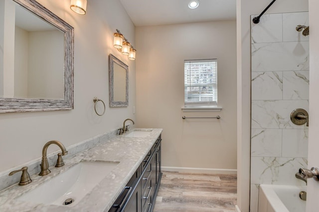 full bath with double vanity, baseboards, a sink, and wood finished floors