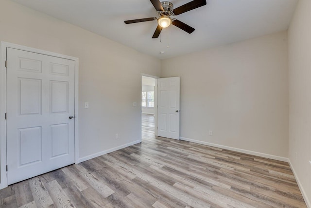 unfurnished room with ceiling fan, light wood-style flooring, and baseboards