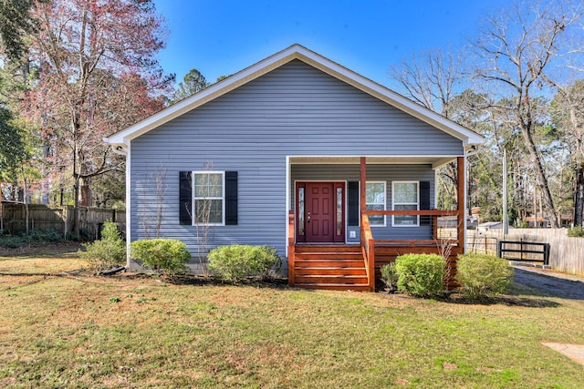 bungalow-style house featuring covered porch, fence, and a front lawn