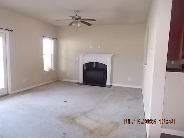 unfurnished living room featuring ceiling fan and light colored carpet