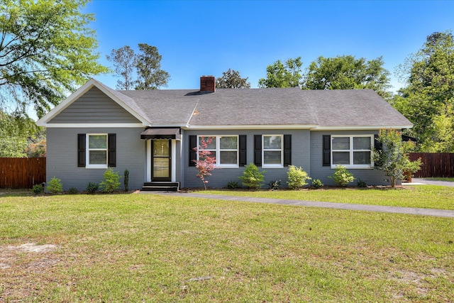 single story home featuring a chimney, a shingled roof, fence, a front yard, and brick siding