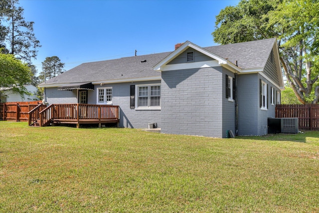 rear view of property with a wooden deck, a fenced backyard, roof with shingles, and brick siding
