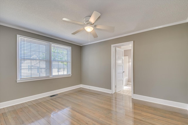 empty room with light wood-style flooring, a textured ceiling, baseboards, a ceiling fan, and crown molding
