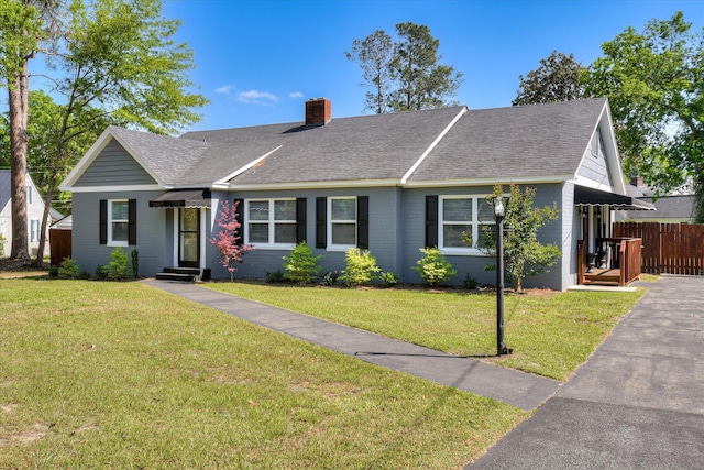 ranch-style house featuring a chimney, a front lawn, and a shingled roof