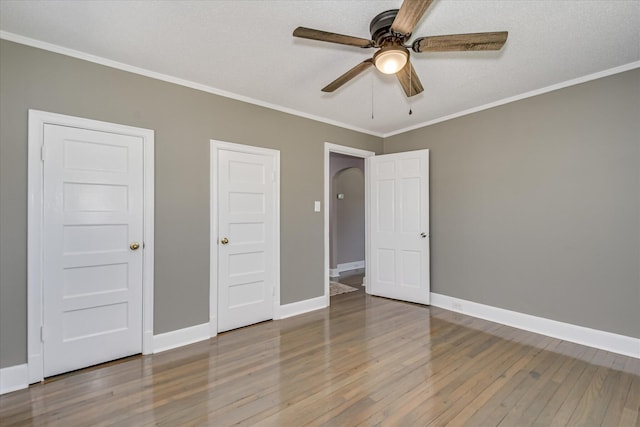 unfurnished bedroom featuring baseboards, a ceiling fan, wood finished floors, and crown molding