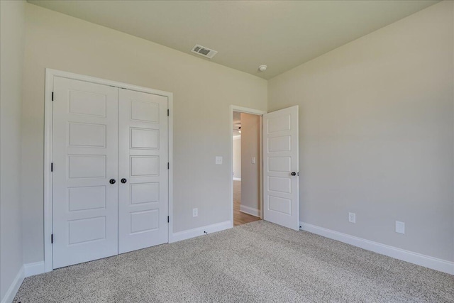 unfurnished bedroom featuring light colored carpet and a closet