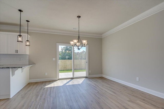 unfurnished dining area featuring crown molding, an inviting chandelier, and light hardwood / wood-style floors