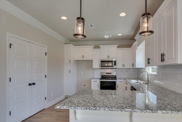 kitchen with sink, hanging light fixtures, backsplash, stainless steel appliances, and white cabinets