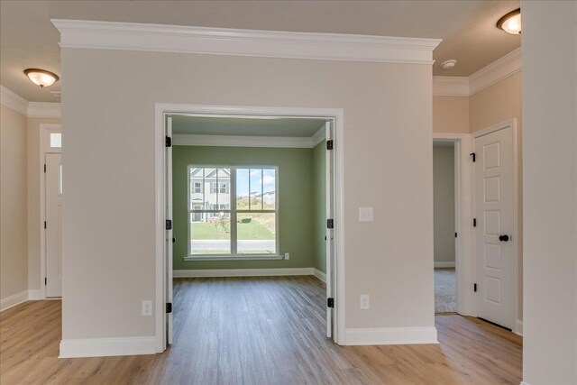 empty room with ornamental molding and light hardwood / wood-style floors