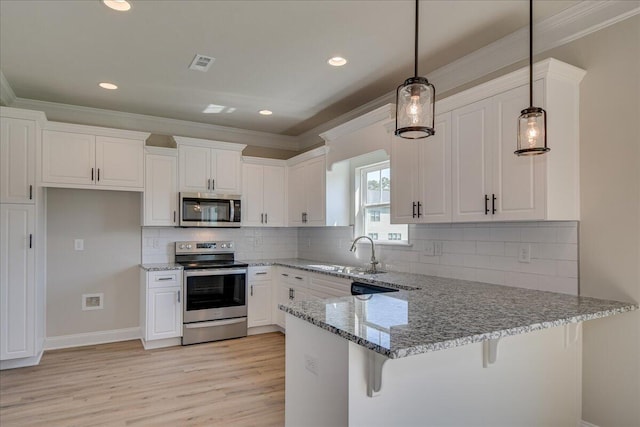 kitchen with pendant lighting, sink, white cabinets, and appliances with stainless steel finishes