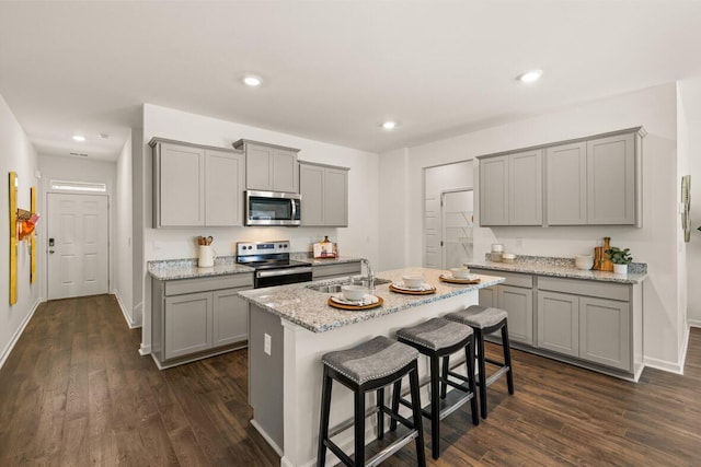 kitchen with stainless steel appliances, gray cabinets, a center island with sink, and sink