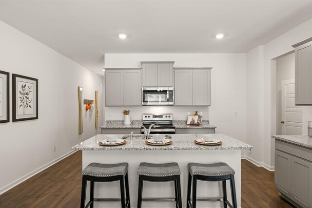 kitchen with dishwasher, a kitchen island with sink, dark wood-type flooring, sink, and gray cabinets