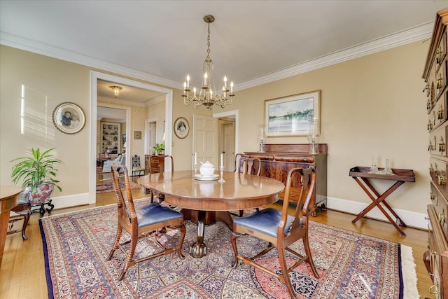 dining area with crown molding, a chandelier, and light hardwood / wood-style flooring